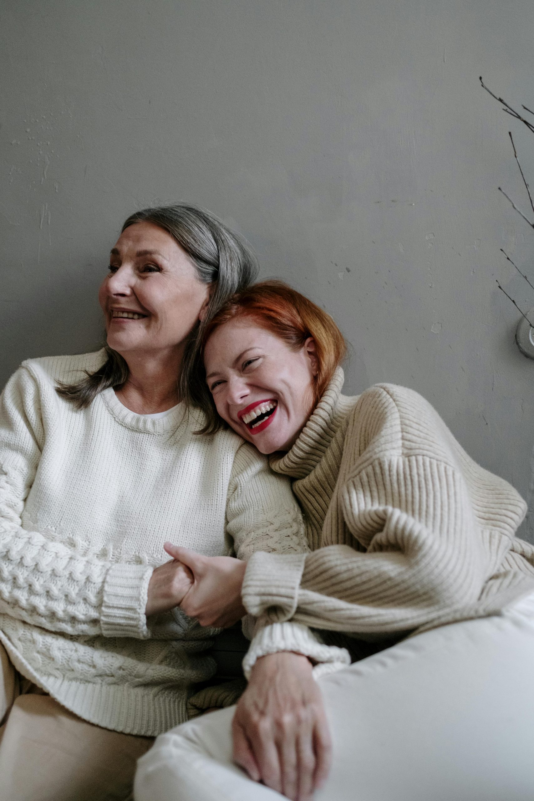 an older woman and a younger woman laughing and side hugging